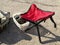 High chair on three legs for fishing. A chair with a red saddle. For fishing. Compact, folding chair for outdoor