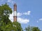 A High Chimney Rises into The Blue Sky Against the Backdrop of Running Snow-White Clouds