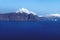 High cliffs along the coastline with blue ocean and white clouds on the village of Fira with white washed houses, Santorini,