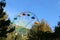 High colorful ferris wheel in the park with blue sky and mountains on the background