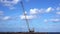 High construction crane next to ocean coast horizon line
