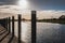 High contrast view of an autumn sunset seen casting shadows against mooring poles seen at a jetty.