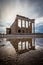 High dynamic range photo of Temple of Athena in Acropolis, seen with reflection on puddle and dramatic sky