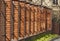 High fence with brick columns. Decorative hedge