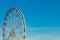 High ferris wheel with multi-colored cabins on a background of blue sky