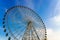 High ferris wheel at sunset or sunrise with cloudy sky background.