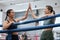 High five with female boxing athlete or fighter and gym partner in the ring of a health and sports club. Young women