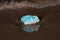 High grade rough natural Amazonite chunk from Madagascar on wet sand  in front of the lake at sunrise