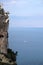 High impregnable cliff with poor mountain vegetation on top and calm sea far and down and Turkish Antalya city on skyline