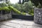 High Iron Gated Driveway Entrance of a Villa. Architectural Garden Landscape Surrounding the Curbed Pathway. Stone and