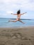 High jump near Athlantic ocean, young sport girl in swimsuit jumps on beach