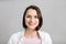 High key portrait of smiling young brunette multiethnic woman in pink tank and white shirt