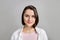 High key portrait of smiling young brunette multiethnic woman in pink tank and white shirt looking at camera