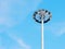 High lamppost with many spotlights in a circle against the blue sky