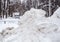 A high large snowdrift by the road against the backdrop of a city street