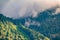 High mountain with green slopes hidden in clouds and fog. Mystical forest on a mountainside in heavy fog