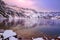 High mountain lake in beautiful violet pint sunset. Mountines is covered with snow