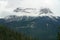 High mountain with snow covered peak and wooded sloped in the foreground