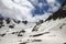 High mountains with avalanche tracks, snowy plateau and cloudy sunlit sky