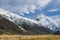 High mountains with snow on top in winter, beautiful sky and clouds. The grass on the road is yellow in Mount Cook Rd