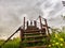 High, old, rusty iron staircase and tiny statue of girl or woman at the top against backdrop of gray, gloomy, thunderous