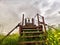 High, old, rusty iron staircase and tiny statue of girl or woman at the top against backdrop of gray, gloomy, thunderous