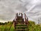 High, old, rusty iron staircase and tiny statue of girl or woman at the top against backdrop of gray, gloomy, thunderous