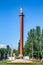 High pillar with a sculpture of the goddess Nike on top in the middle of a city street in