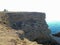 A high precipitous coastal rocky cliff with a tourist bus on top.