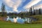 High Pressure Weather Clouds Reflected in Calm Blue Water with Green Grass and Distant Mountain Peaks on Horizon