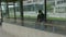 High quality picture of a young man who is waiting for a transportation in a glass bus stop or station and holding his cell phone