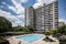 high-rise apartment building with open lobby and swimming pool visible in the background