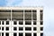 High-rise modern apartment building construction with flat roof and penthouses over blue sky with white clouds