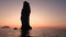 High rock in Mediterranean sea against horizon and Lipari Island. Colorful sky, summer sunrise or sunset. Rippling water