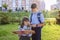 High school brother and sister with a book in their hands on the street of a city park