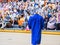 High school graduate with music notes on his mortar board walks toward audience