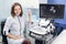 High-skilled professional attractive woman doctor sonographer using ultrasound machine at work, smiling and looking at