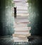 High stack of books with climbing businessman hang on it