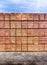 High stacks of orange bricks in storage and ready for shipping to builders under a blue sky and on black asphalt