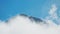 high steep rocky mountain ridge on blue sky background surrounded by moving clouds. beautiful mountain at sunny day with