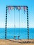 High swing decorated with colorful ribbons against the background of the sea - a place for rest