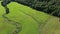 High view angle with a drone, flying over a field, revealing the country landscape, with woods and mountains in the country