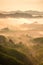 High views with views of mountains and fog interspersed among lush green forests at sunrise, golden light, sky and colorful clouds