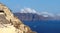 High volcanic cliffs along the coastline with blue ocean and white clouds over the village of Fira with white houses, Santorini,