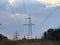 High voltage electric tower against a cloudy sky. High steel power pole, among the forest