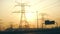 High voltage electrical lines at sunset. Dark silhouette of towers in the rays of evening sun. Distribution and supply of electric