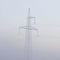 High voltage electricity transfer lines and pylon in a fog