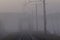 High voltage electricity transfer lines and pylon in a fog