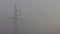 High voltage electricity transfer lines and pylon in a fog