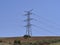 A High Voltage Electricity Transmission Pylon with its suspended overhead Cables on top of a small Hill near Alora.